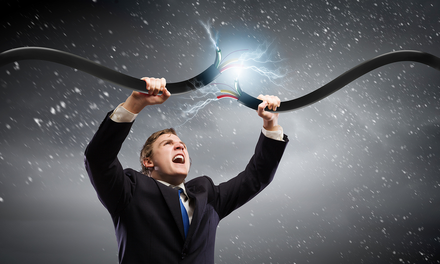 Young businessman tearing electricity cable with hands